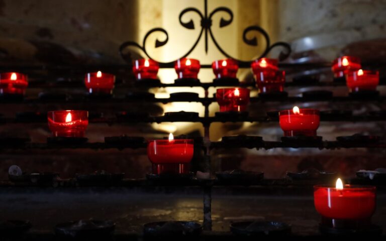 Red candles glowing in a church setting, providing a warm and serene atmosphere.