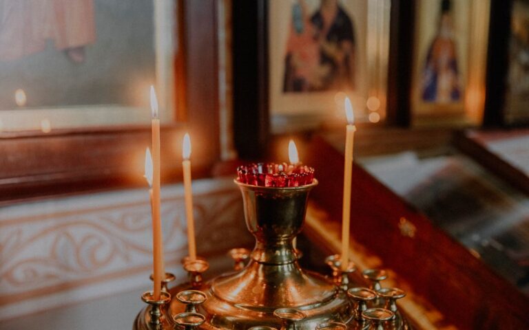 Softly lit church candles next to orthodox icons creating a warm, spiritual ambiance.