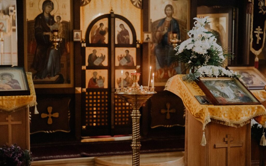 Beautifully adorned Orthodox church interior with icons, candles, and altar.