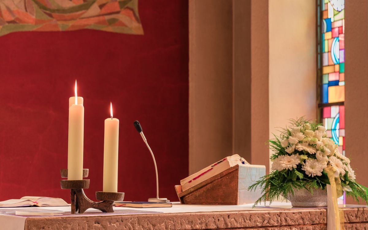 A peaceful church altar scene in Pfinztal, Germany, featuring lit candles and floral arrangements.