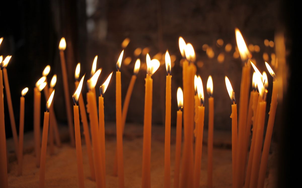 A serene scene of lit votive candles during a religious ceremony in a Larnaka church.