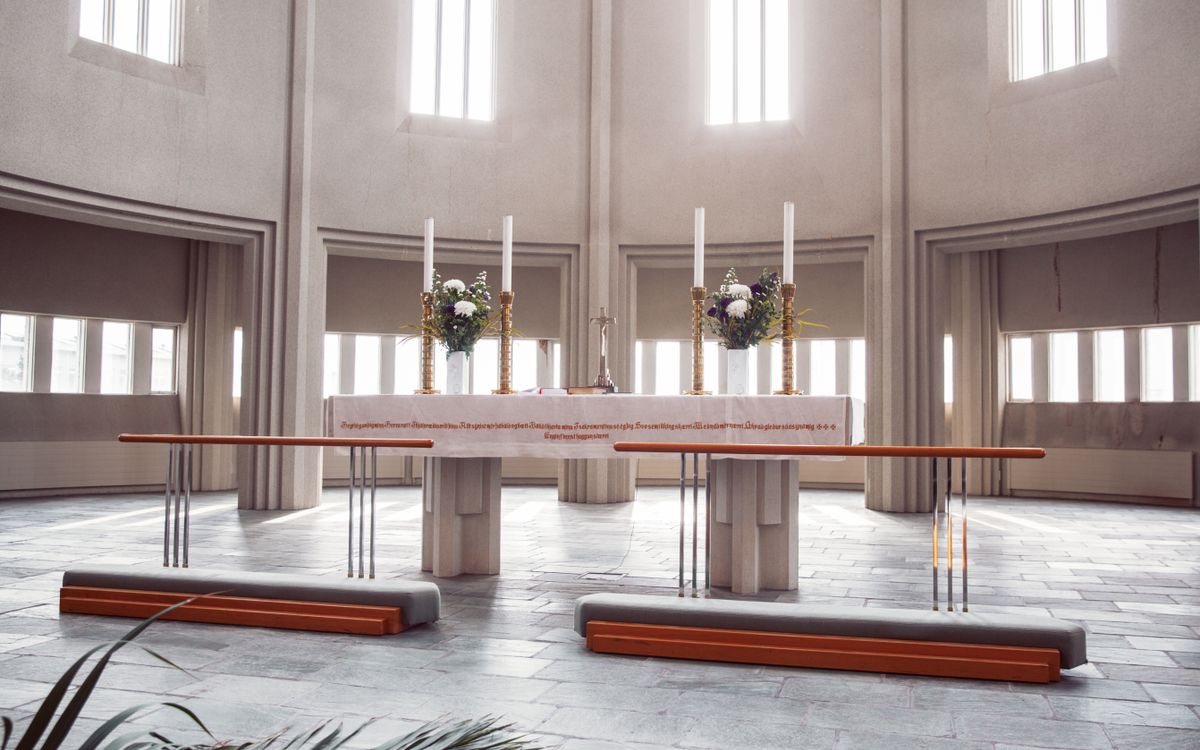 A spacious modern church altar with candles, flowers, and natural light.