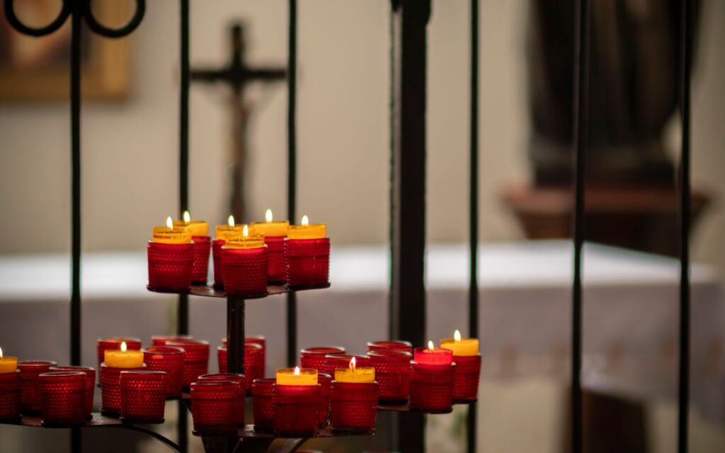Warm ambiance with red votive candles and cross in a Polish church indoors.