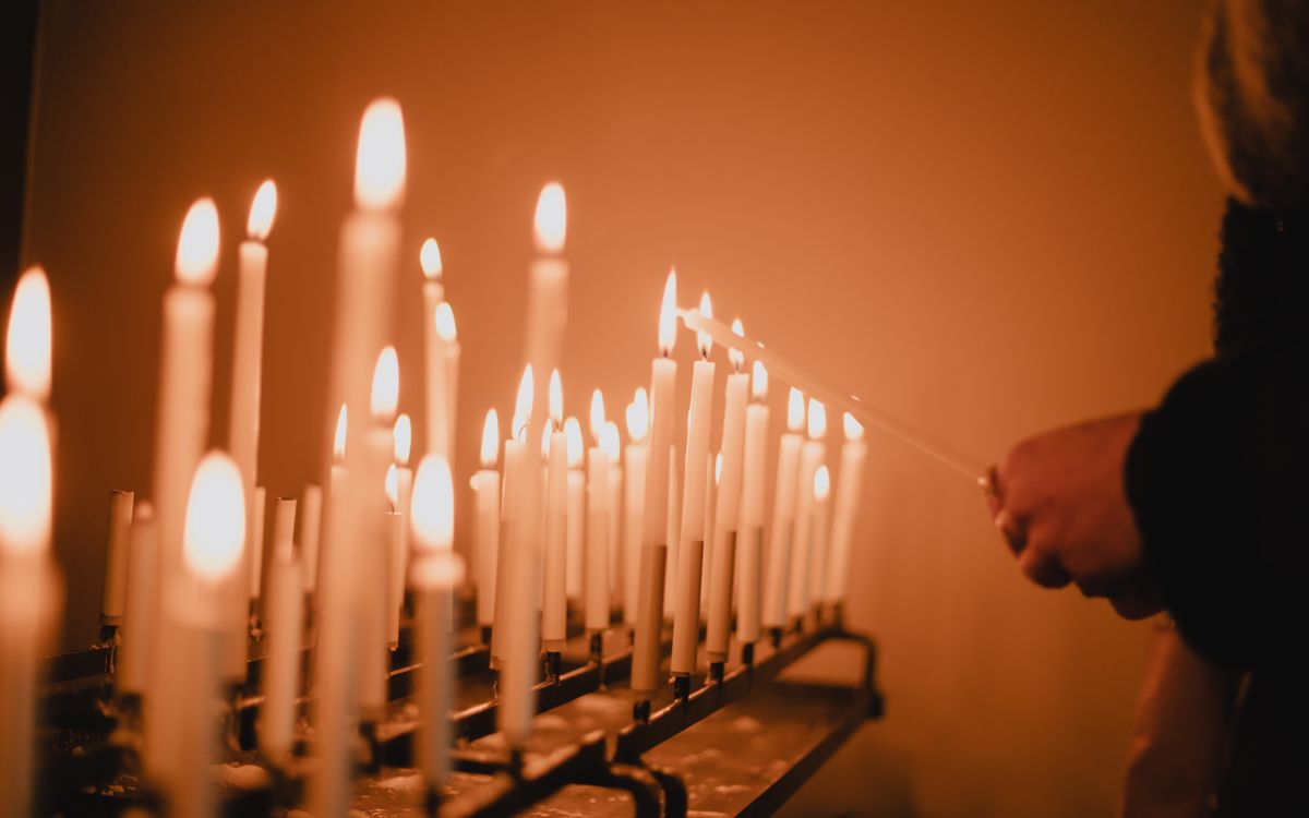 Multiple candles lit during a solemn vigil in a Maastricht church, evoking a serene and spiritual atmosphere.