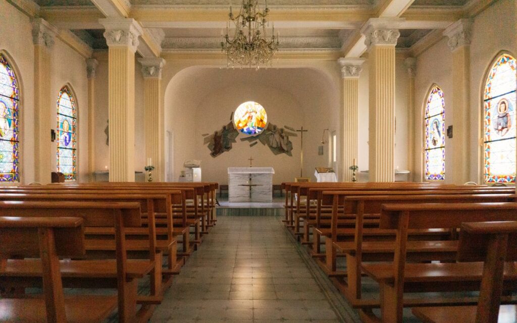 Peaceful church interior featuring elegant stained glass windows and wooden pews.
