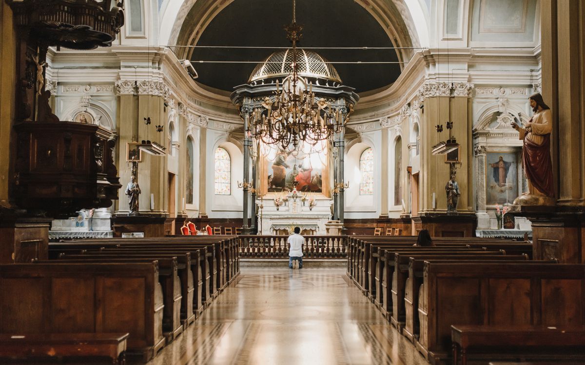 Stunning baroque church interior featuring an ornate altar, chandeliers, and wooden pews.