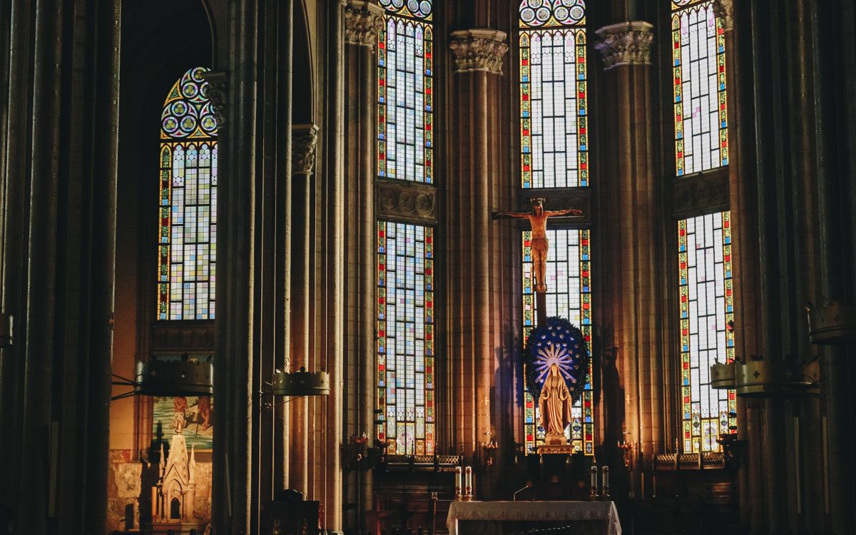 Beautiful stained glass windows and altar in a historic cathedral interior.